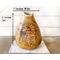 A handmade sunflower vase decorates an entryway table. It is 11 by 7 inches. The vase is made from a dried gourd. 